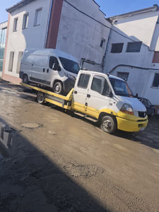 Zi, curte interioară a unei clădiri. O dubă Peugeot Boxer albă este încărcată integral pe platforma galbenă a mașinii de tractare, pregătită pentru transport.